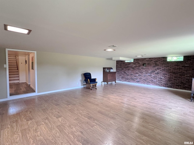 unfurnished room featuring light hardwood / wood-style floors and brick wall