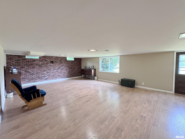 unfurnished room featuring a healthy amount of sunlight, light wood-type flooring, and brick wall