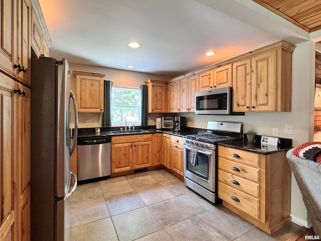 kitchen featuring sink, stainless steel appliances, light tile patterned floors, and dark stone countertops