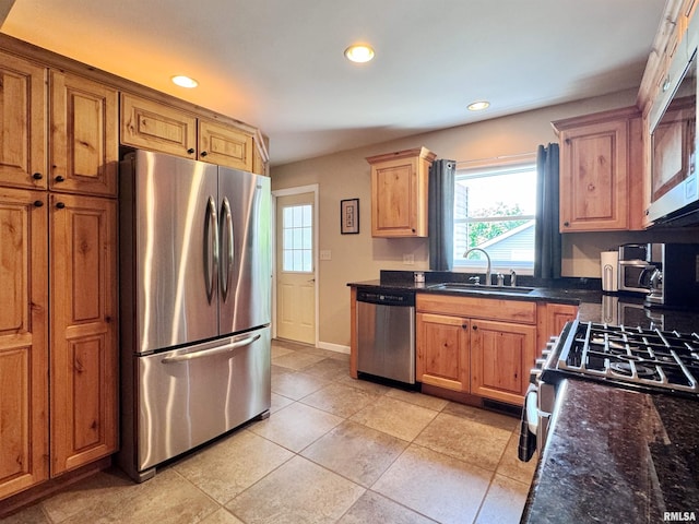 kitchen featuring sink, stainless steel appliances, light tile patterned floors, and dark stone countertops