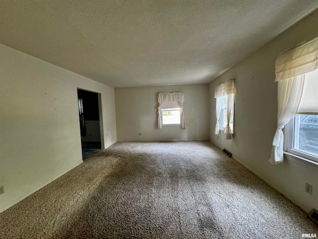 carpeted spare room with a textured ceiling