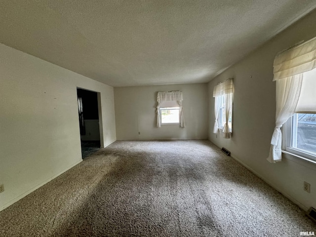 unfurnished room with a textured ceiling, carpet flooring, and visible vents