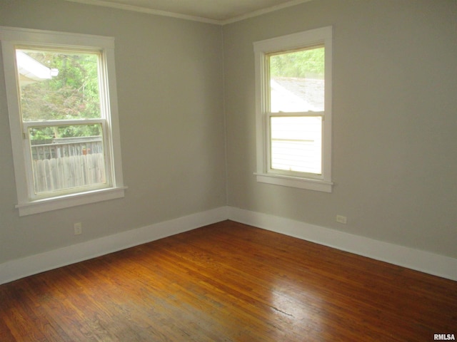 empty room featuring dark hardwood / wood-style flooring, a wealth of natural light, and crown molding