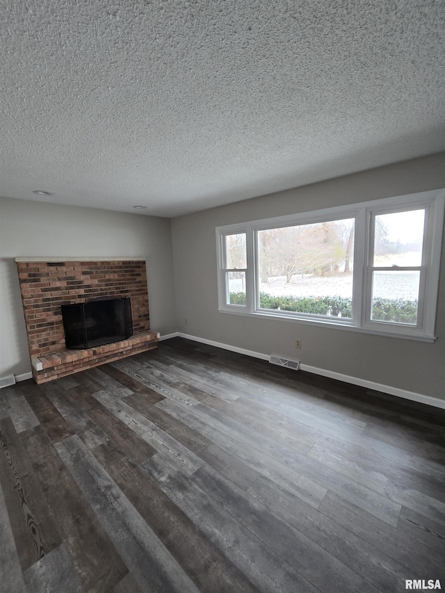 1638 Knox Highway 15, Dahinda, IL 61428 - unfurnished living room featuring dark wood finished floors, baseboards, a brick fireplace, and a textured ceiling