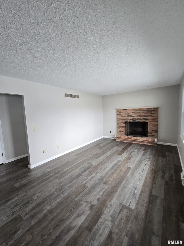 1638 Knox Highway 15, Dahinda, IL 61428 - unfurnished living room with dark wood-style flooring, a textured ceiling, a brick fireplace, and baseboards
