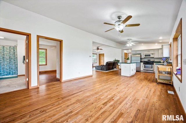 kitchen featuring stainless steel appliances, kitchen peninsula, white cabinets, and light hardwood / wood-style flooring