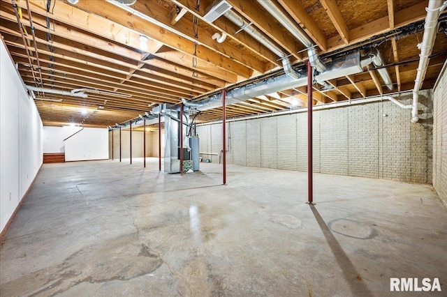 basement featuring water heater and brick wall