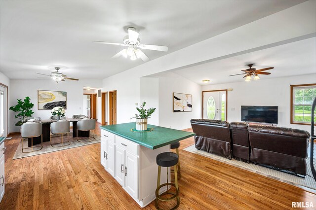 kitchen with white cabinetry, a center island, a breakfast bar, and light hardwood / wood-style flooring