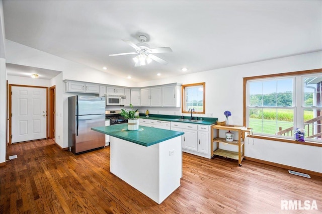 kitchen featuring sink, ceiling fan, appliances with stainless steel finishes, white cabinetry, and wood-type flooring