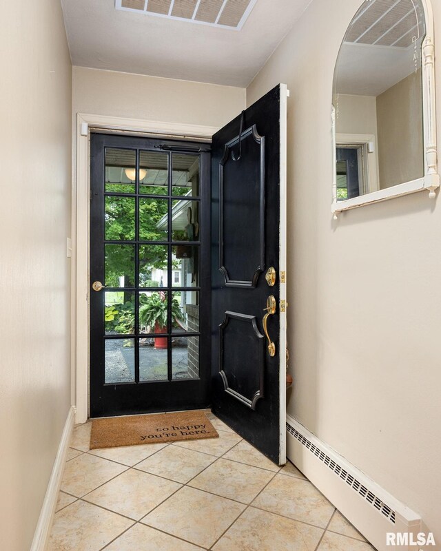 entryway with light tile patterned flooring, baseboard heating, and plenty of natural light