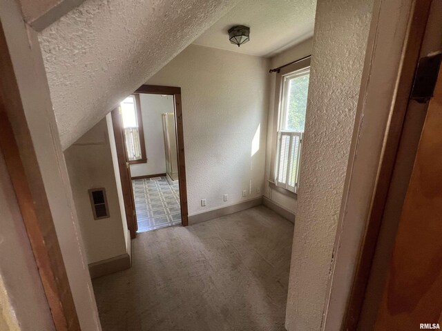 additional living space featuring carpet flooring and a textured ceiling