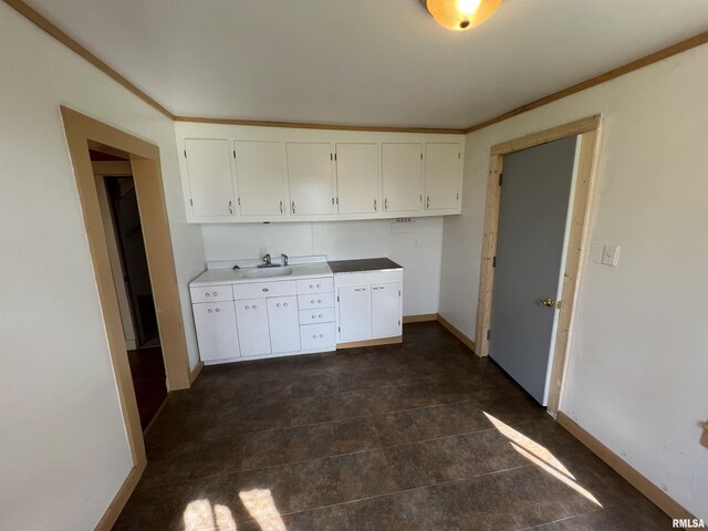 kitchen featuring white cabinets, ornamental molding, and dark tile patterned floors