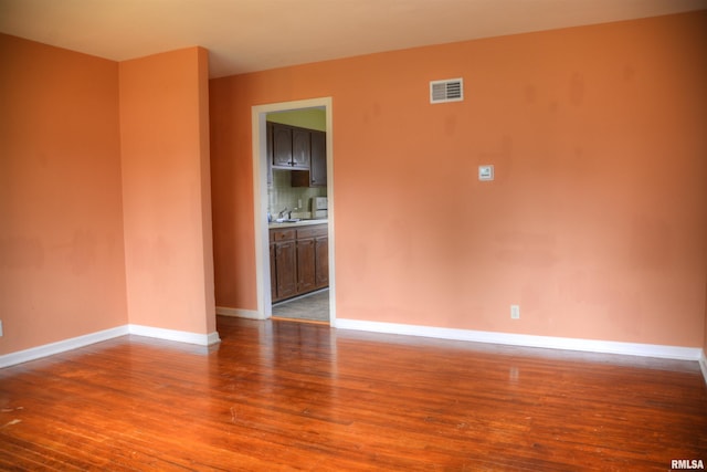 spare room with hardwood / wood-style floors and sink