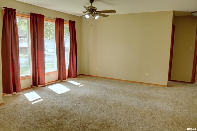 empty room featuring ceiling fan, light carpet, and a wealth of natural light