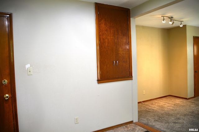 spare room featuring light carpet and rail lighting