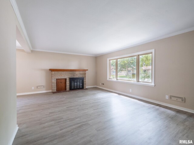 unfurnished living room with crown molding, wood-type flooring, and a stone fireplace