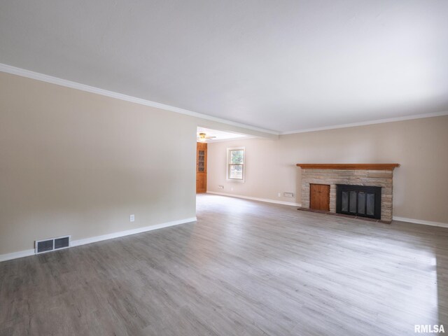 unfurnished living room with hardwood / wood-style floors, crown molding, a stone fireplace, and ceiling fan