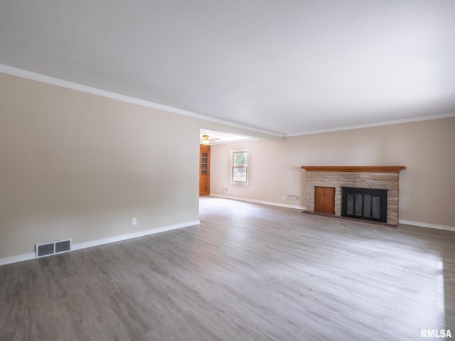 unfurnished living room with ornamental molding, a stone fireplace, and hardwood / wood-style floors