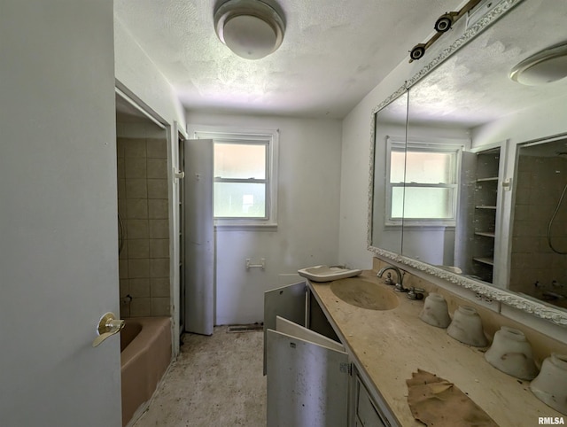 bathroom with vanity, tiled shower / bath combo, a textured ceiling, and a healthy amount of sunlight