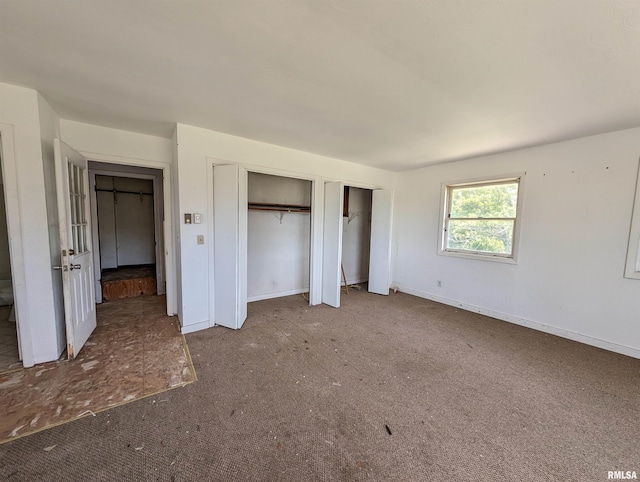 unfurnished bedroom featuring multiple closets and carpet flooring