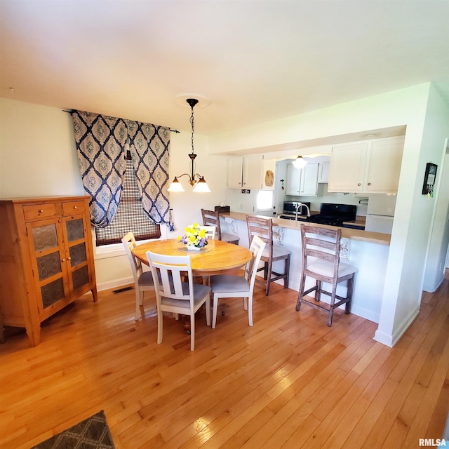 dining area with ceiling fan with notable chandelier and light wood-type flooring