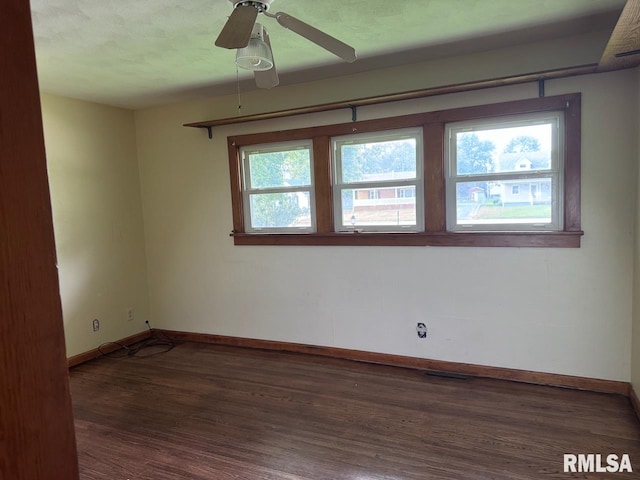 spare room featuring ceiling fan, plenty of natural light, and dark wood-type flooring