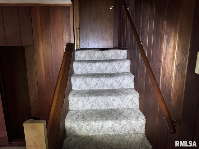 stairway featuring wood walls