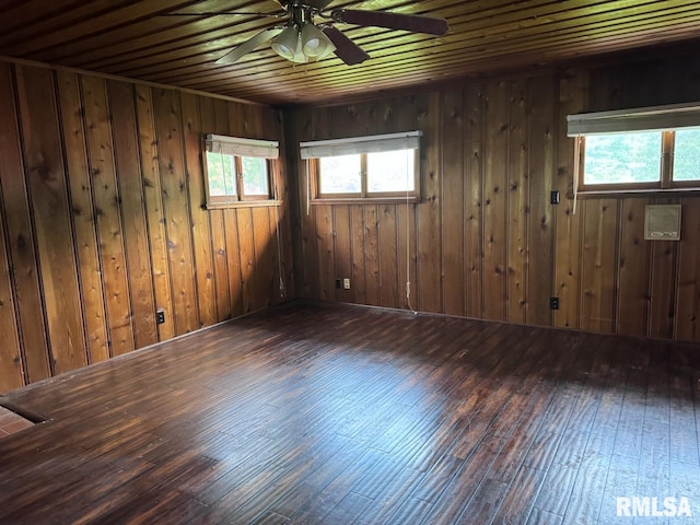 empty room with wood ceiling, wood walls, ceiling fan, and dark hardwood / wood-style flooring