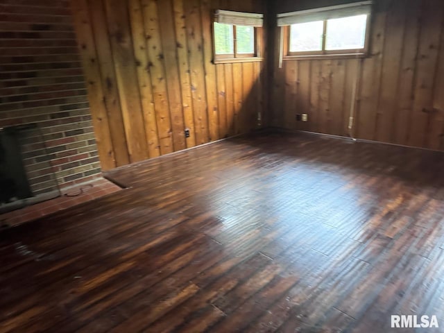 unfurnished living room with a fireplace, wood walls, and dark hardwood / wood-style floors