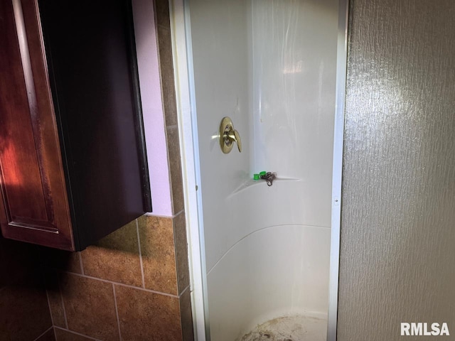 bathroom featuring walk in shower and tile walls