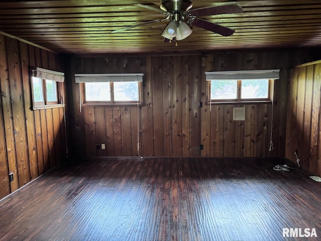 spare room with wood walls, ceiling fan, and dark wood-type flooring