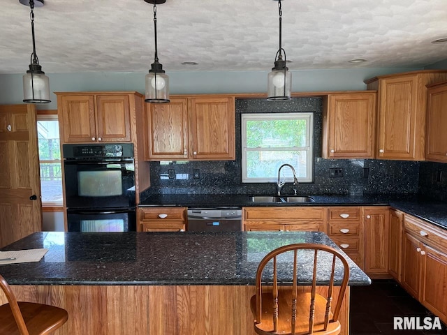 kitchen with hanging light fixtures, black appliances, sink, and a breakfast bar