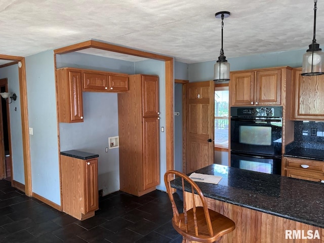 kitchen featuring a textured ceiling, hanging light fixtures, backsplash, and black double oven