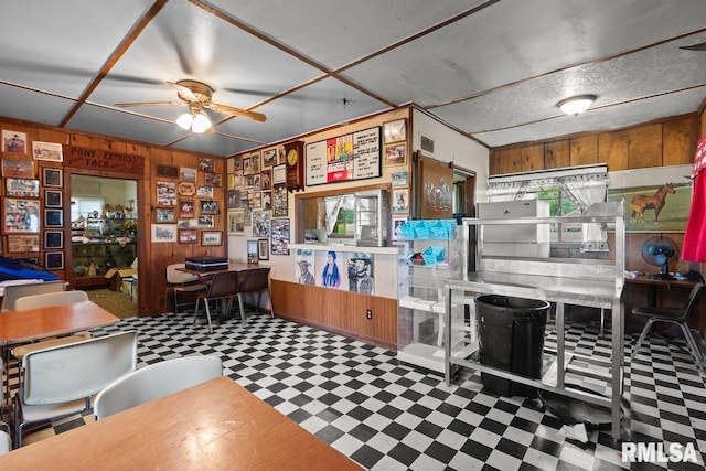 interior space featuring ceiling fan, wood walls, and tile patterned floors