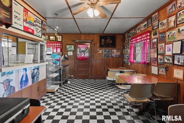 office space with tile patterned floors, ceiling fan, and wood walls