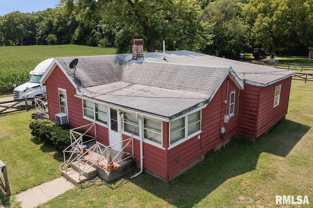exterior space with a lawn, a chimney, fence, and central AC