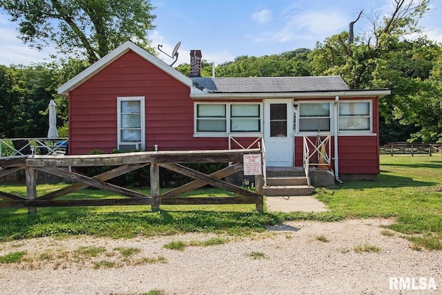 view of front of home with a front lawn, solar panels, and fence