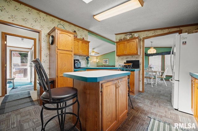 kitchen with a wealth of natural light, a center island, lofted ceiling, and white refrigerator