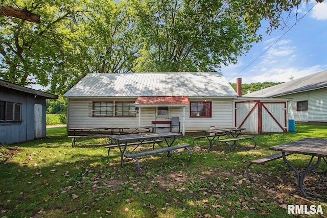 rear view of property featuring an outbuilding, a yard, and metal roof