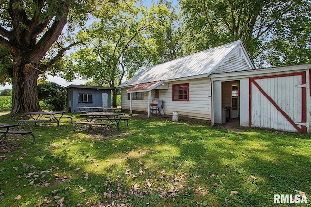 back of house with a lawn, metal roof, and an outdoor structure