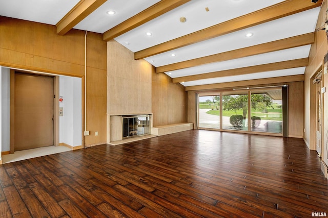 unfurnished living room featuring dark hardwood / wood-style floors, elevator, wooden walls, vaulted ceiling with beams, and a premium fireplace