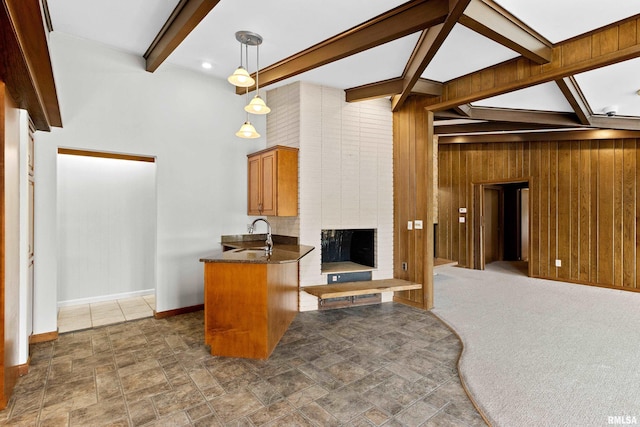 kitchen with pendant lighting, sink, beam ceiling, wooden walls, and kitchen peninsula