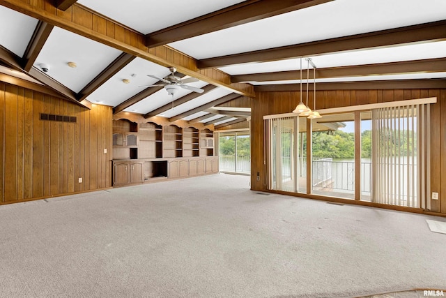 unfurnished living room with built in shelves, carpet floors, wooden walls, and lofted ceiling with beams