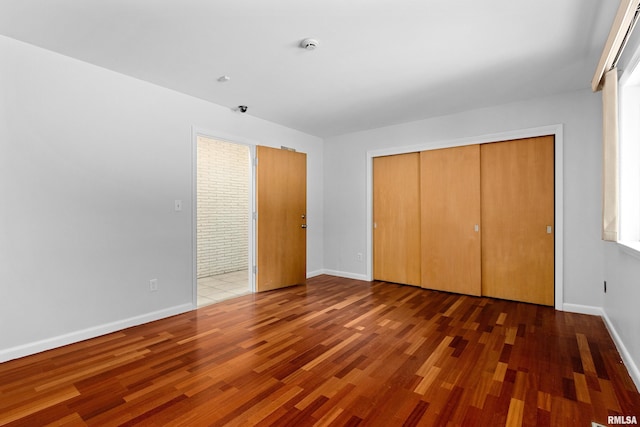 unfurnished bedroom with dark hardwood / wood-style flooring and a closet