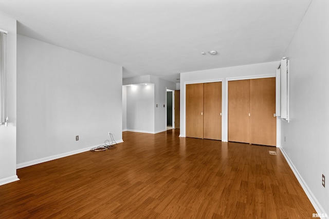 unfurnished bedroom with hardwood / wood-style floors and two closets