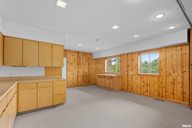 kitchen featuring sink, light carpet, light brown cabinets, and wood walls