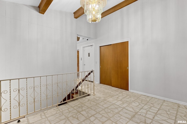 spare room with a high ceiling, a notable chandelier, and beam ceiling