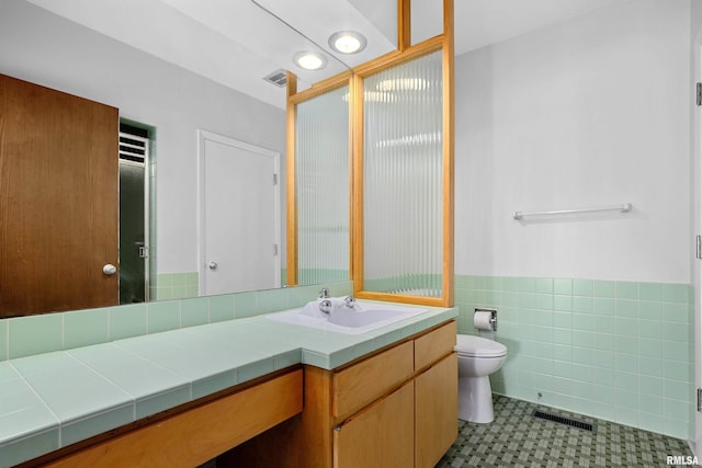 bathroom with tile walls, vanity, and toilet