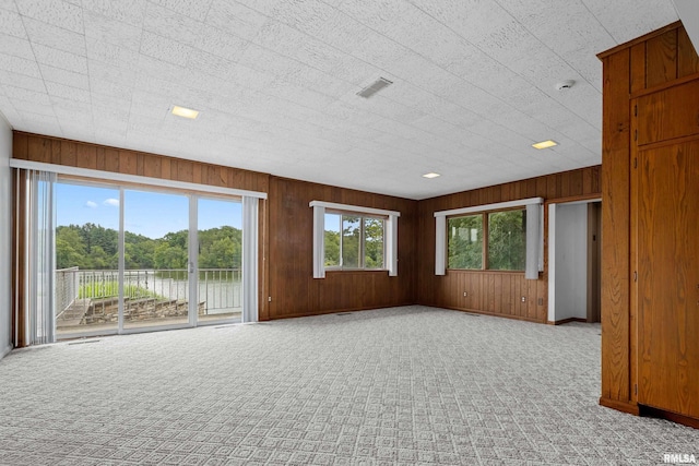 carpeted empty room with wood walls