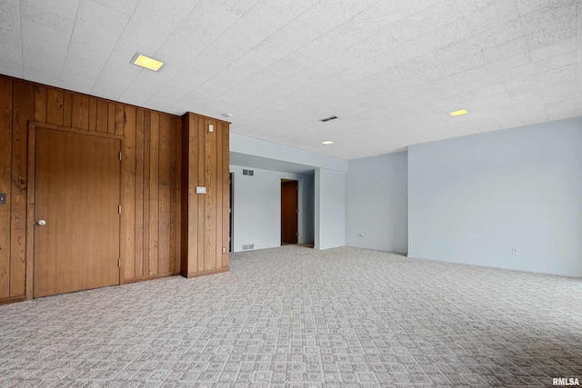 unfurnished room featuring wooden walls and light carpet